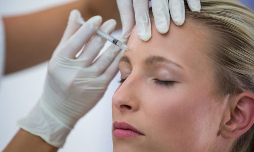 Close-up of female patient receiving a botox injection on forehead