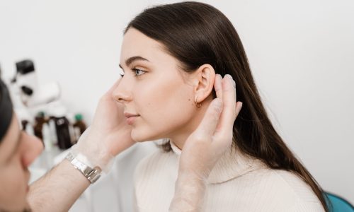Otoplasty is surgical reshaping of the pinna, or outer ear for correcting an irregularity and improving appearance. Surgeon doctor examines girl ear before otoplasty cosmetic surgery