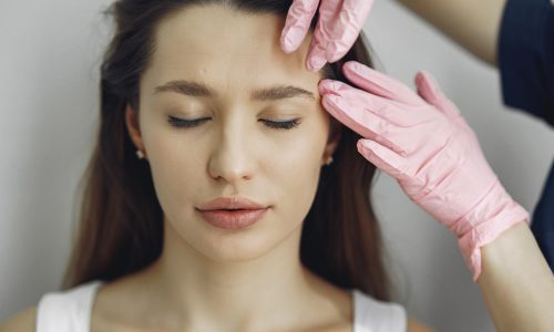 Cosmetologist holds hands near client's face. Woman with cosmetologist. Lady in a beauty studio.