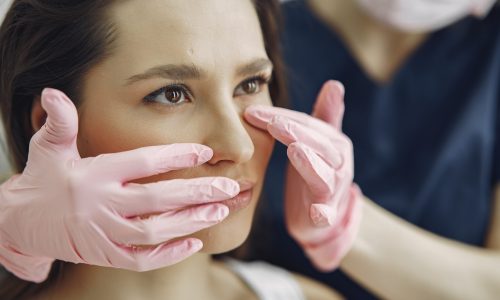 Cosmetologist holds hands near client's face. Woman with cosmetologist. Lady in a beauty studio.